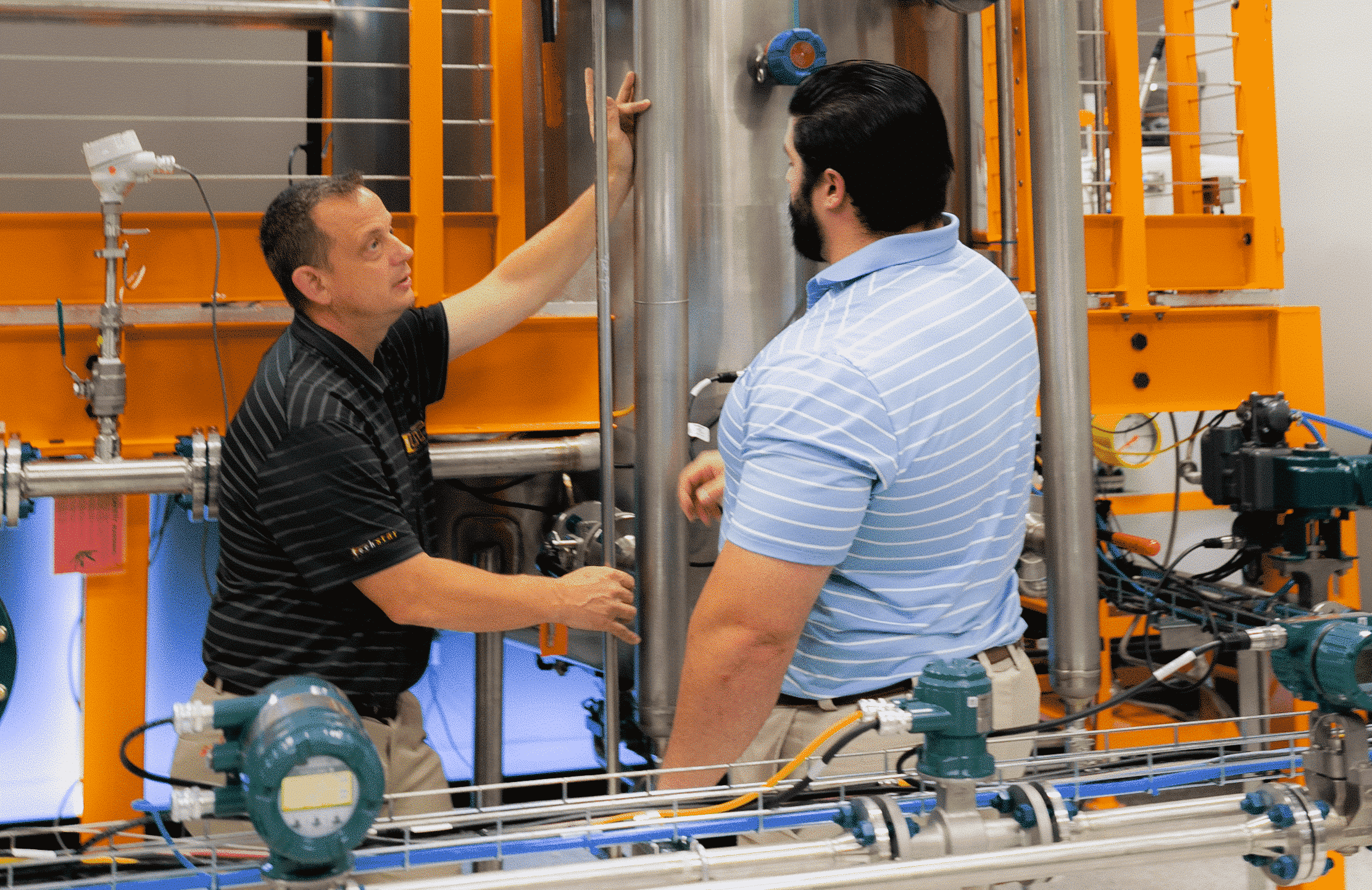 Two men are discussing and training on the use of various valves and measurement instrumentation